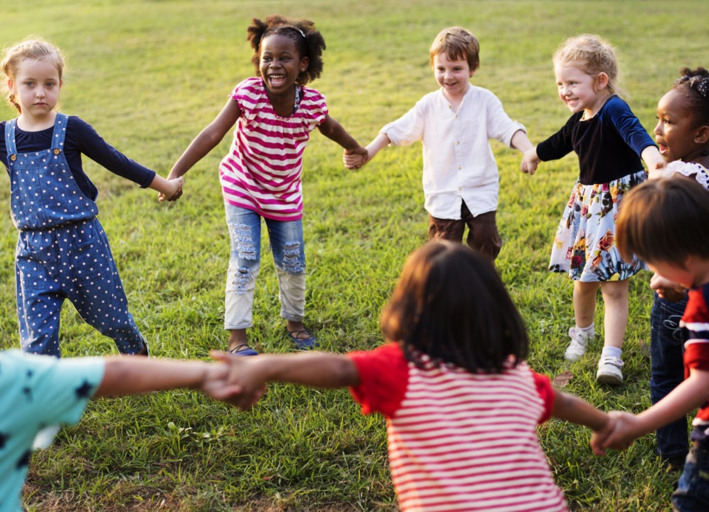 Children hold hands in a circle and play outdoors