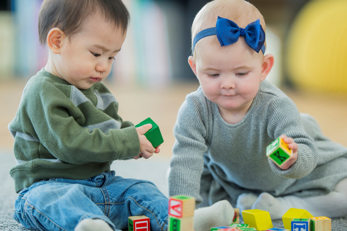 Two babies playing with blocks