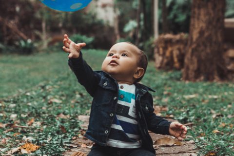 toddler reaching for blue ball in air