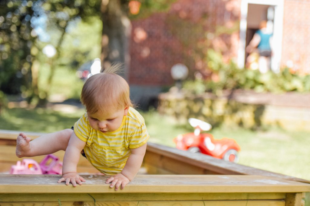 A baby climbing out of a play pen