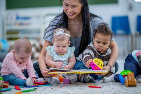 A woman reading to three babies