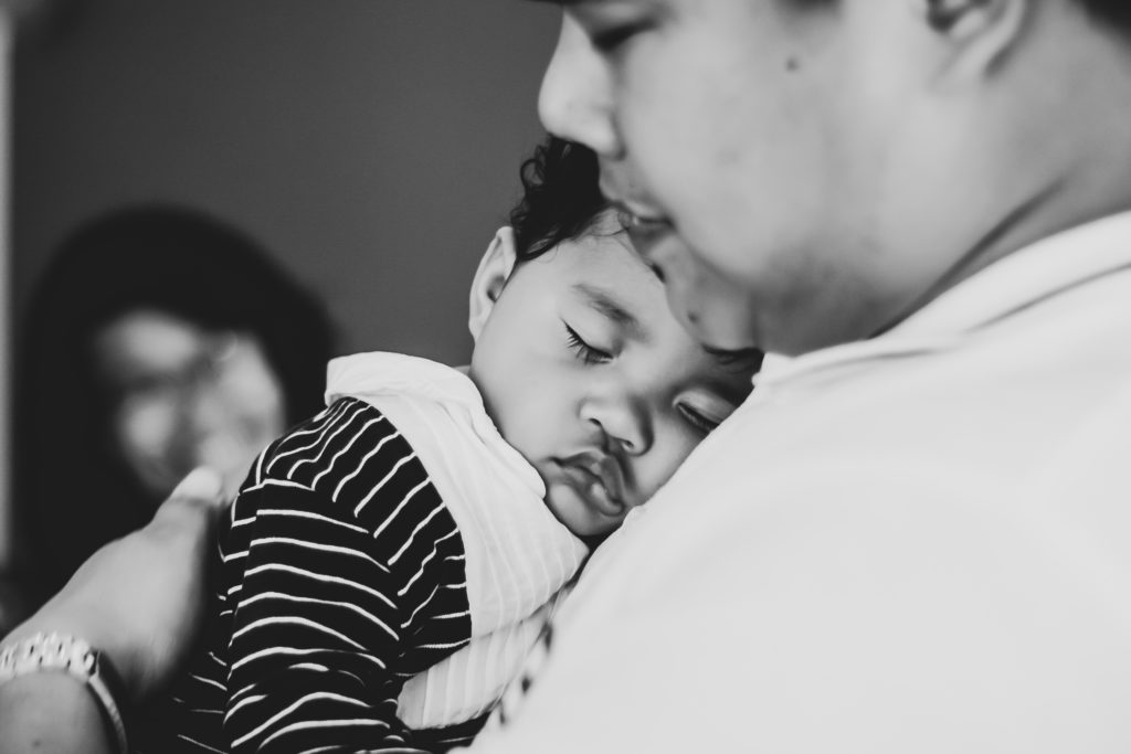 A sleeping toddler lays on a man's chest