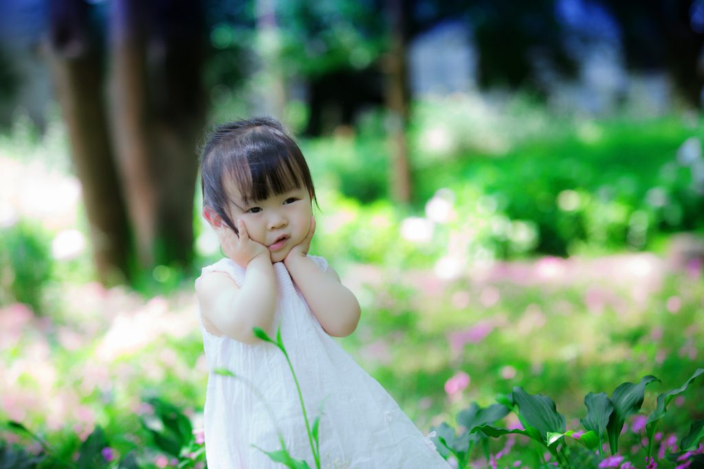 girl sits outside in a patch of grass and flowers