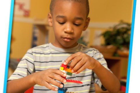 A young Black boy plays with Lego blocks