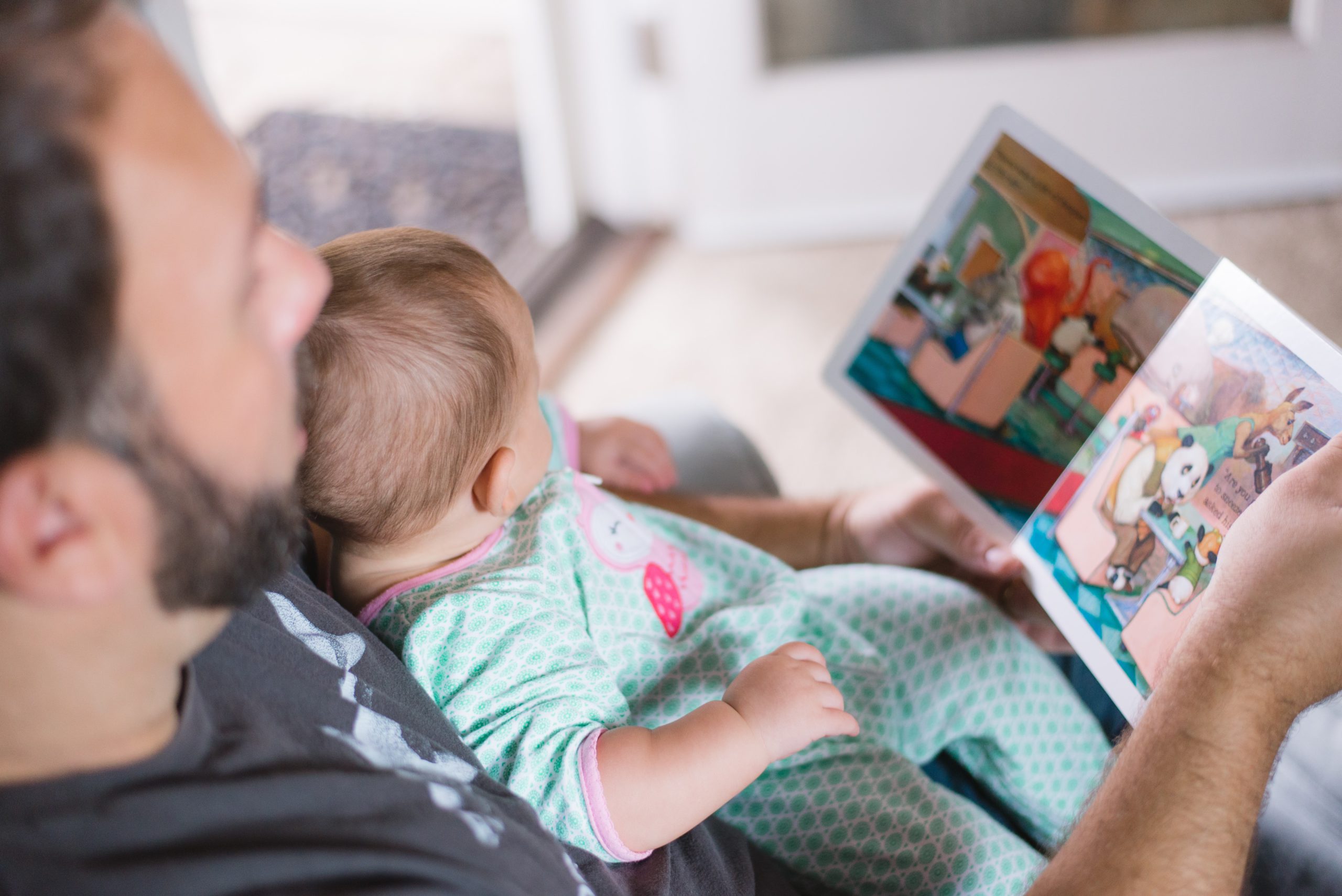 a man reads a picture book to a baby