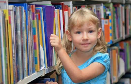 A girl picks out a book from a shelf