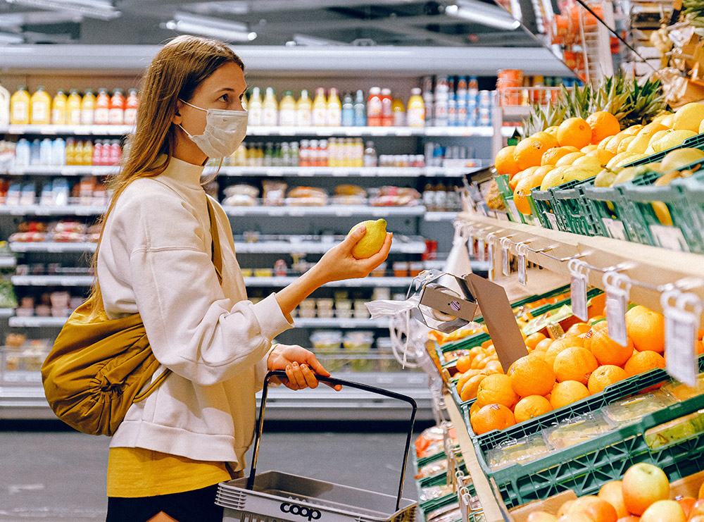 woman shopping for lemons in mask at grocery store
